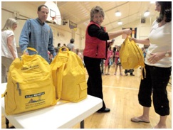 Volunteers pass out emergency kits in yellow backpacks