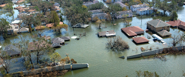 Flood waters pouring through a broken levee into a neghborhood of houses