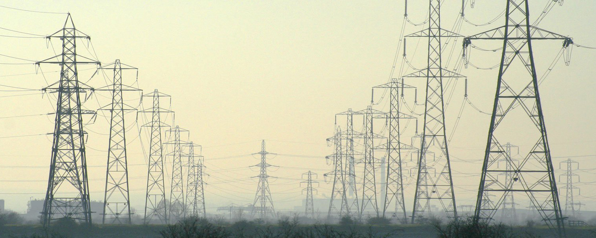 A series of electric power lines over a foggy field