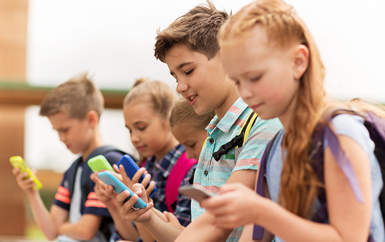 Kids sitting in a row looking at their cell phones