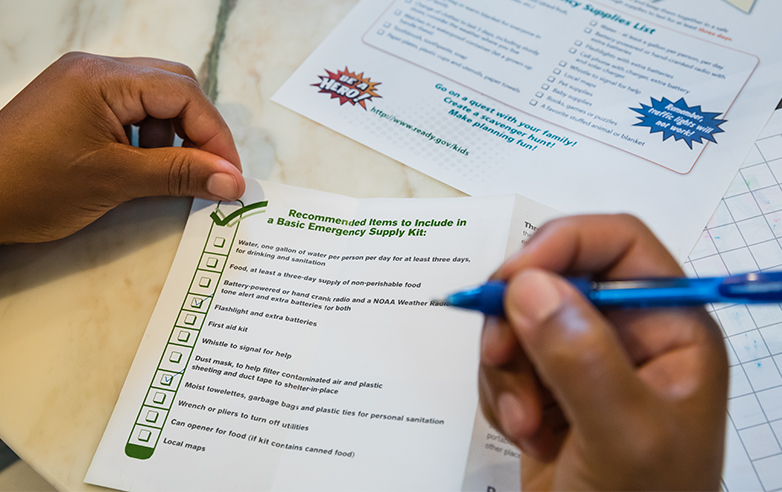 Person reviewing a checklist of the recommended items to include in a basic emergency supply kit