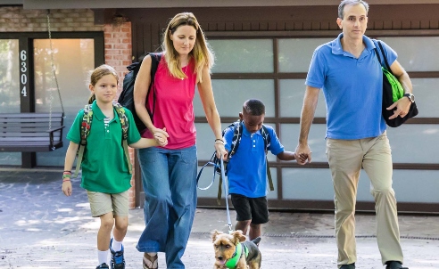Two parents walking with their kids from their house