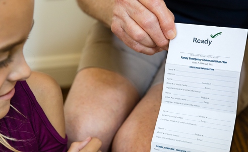 Child reviewing a checklist for preparedness planning with their parent