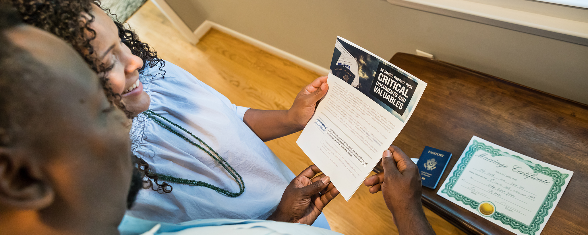 A couple looks at a document on securing documents and valuables, with their marriage license and passport on the table