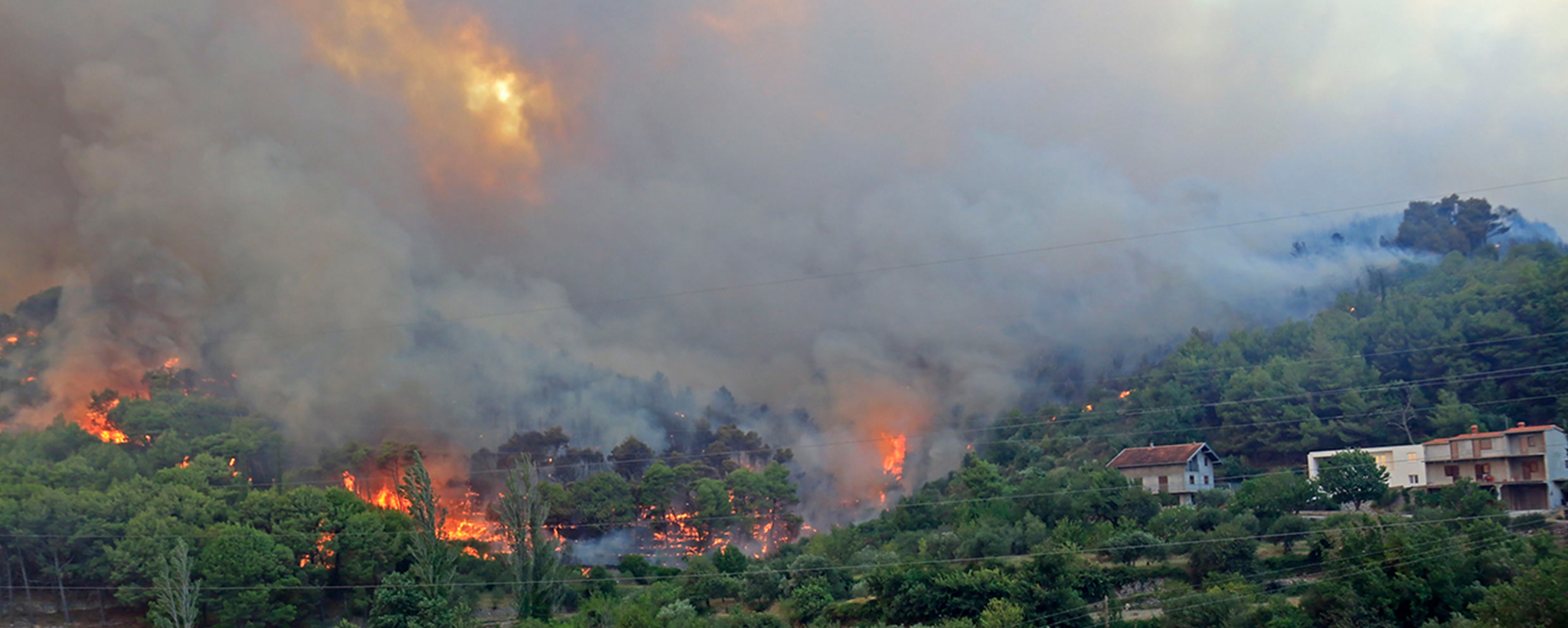 Fire on a hillside behind houses