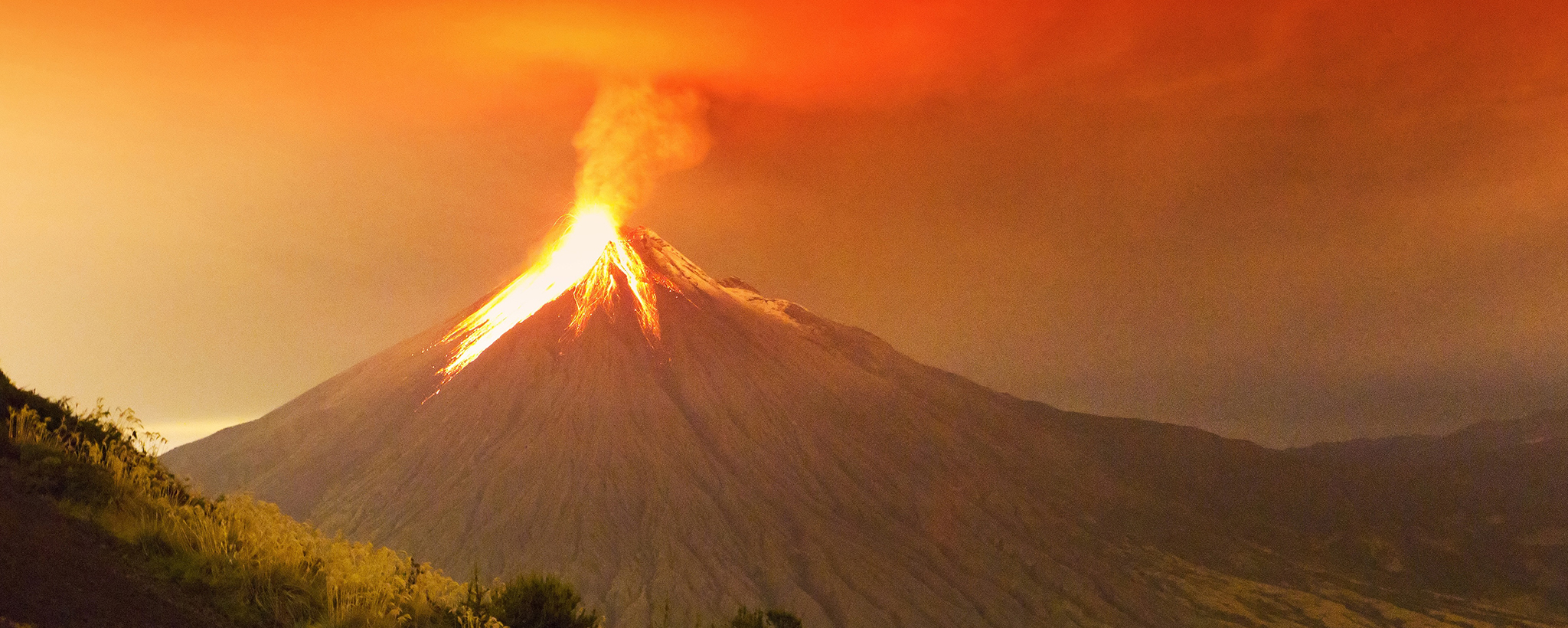 A volcano in the early stages of eruption with lava and smoke beginning to flow out of the opening