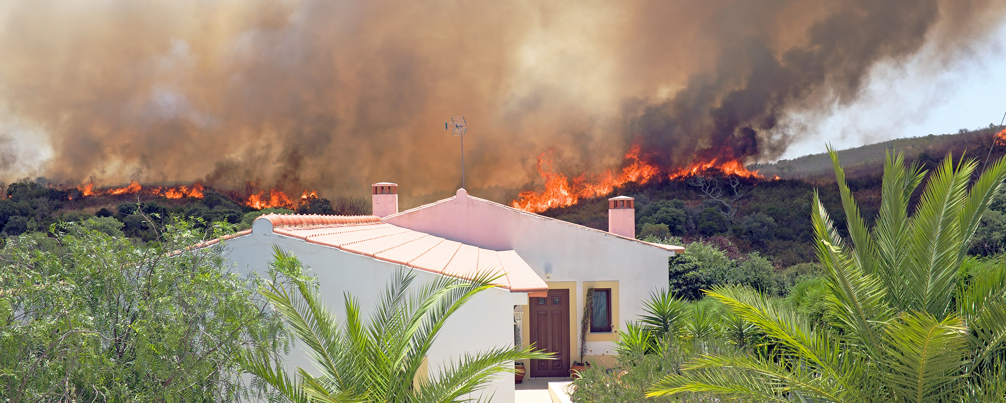 un incendio forestal arde cerca de una casa