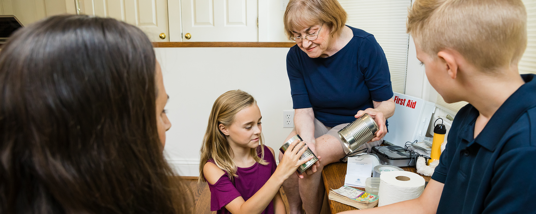 A grandmother builds hands her granddaughter cans for an emergency supply kit.