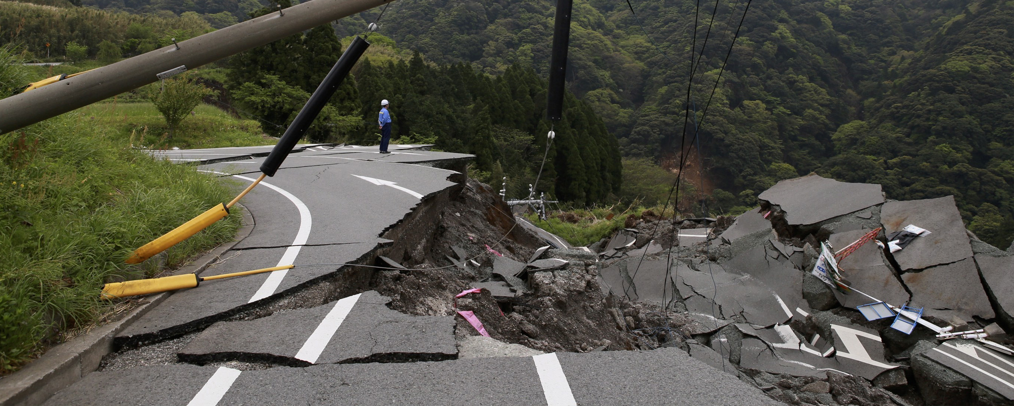 A road has a crack down the center, where the road has crumbled after an earthquake.