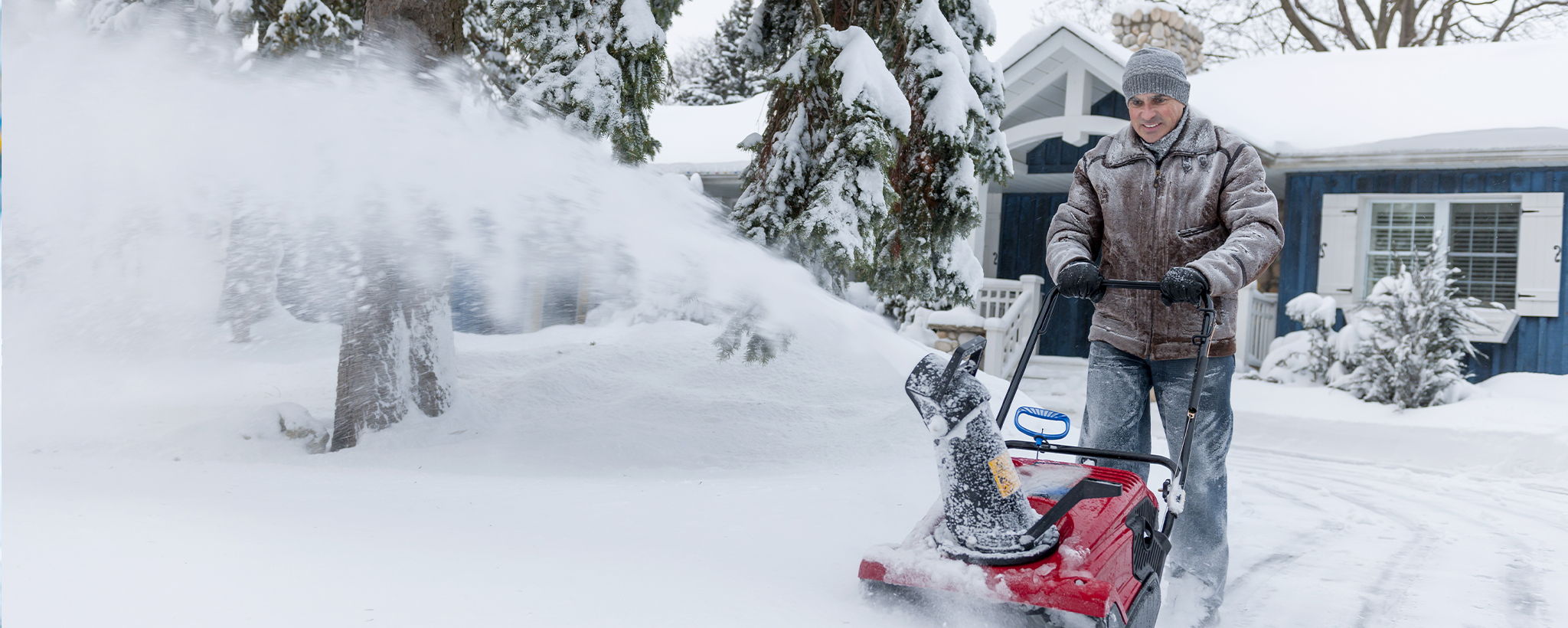 A man using a snow blower to clear snow. 