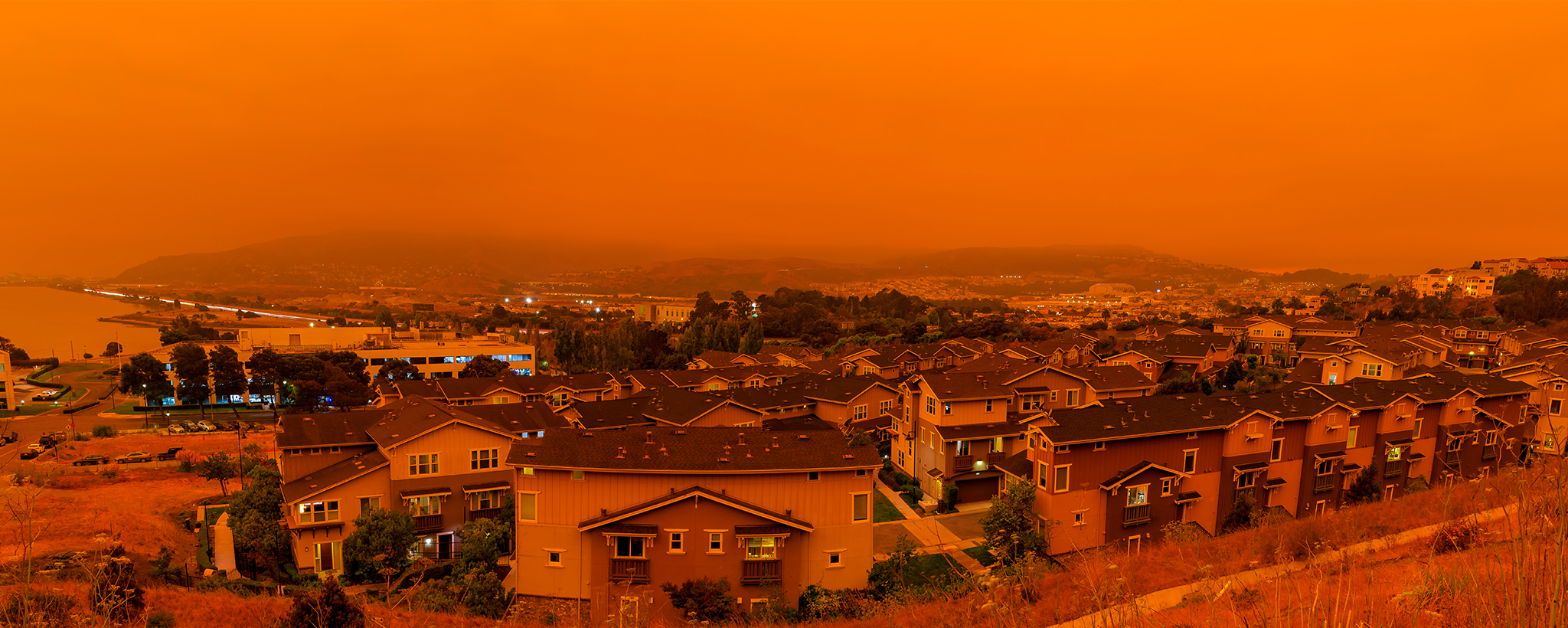 Neblina naranja sobre casas de un incendio forestal cercano.