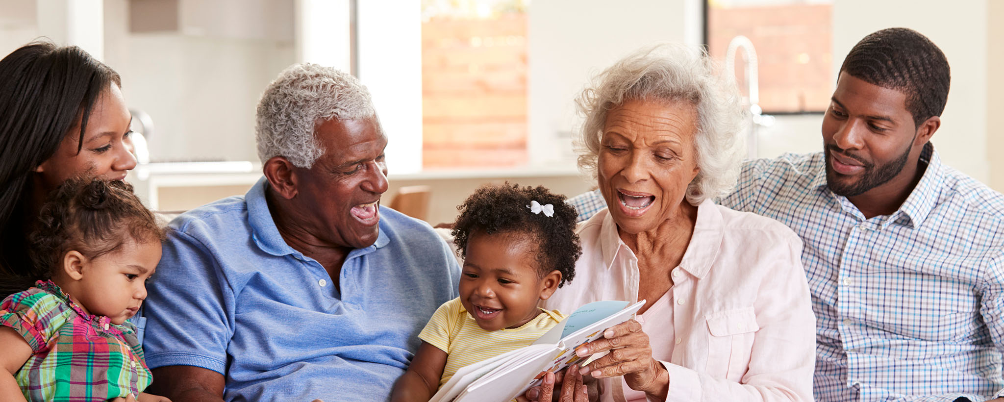 multi-generational black family sitting together looking at a book
