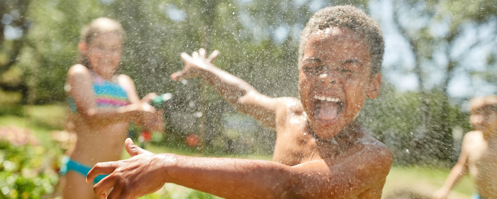 children play in a water sprinkler