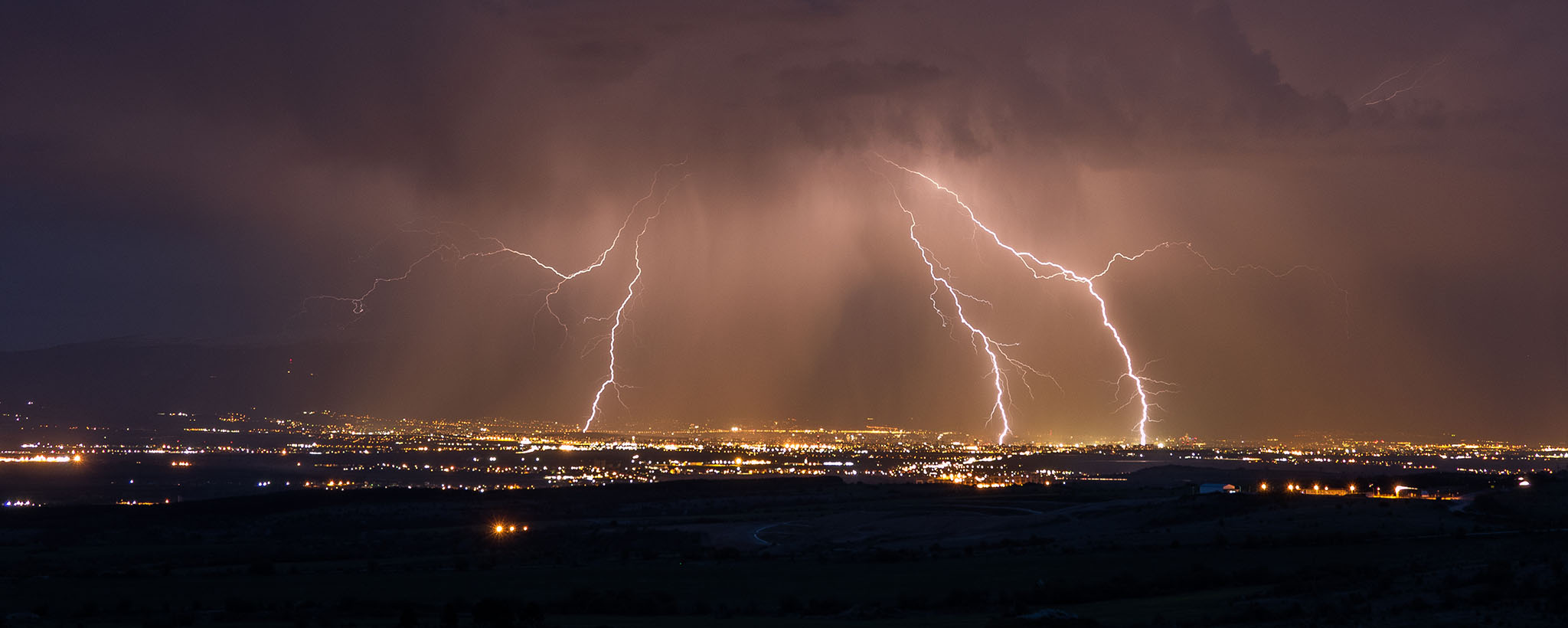 lightning striking a city in several places, as seen from afar