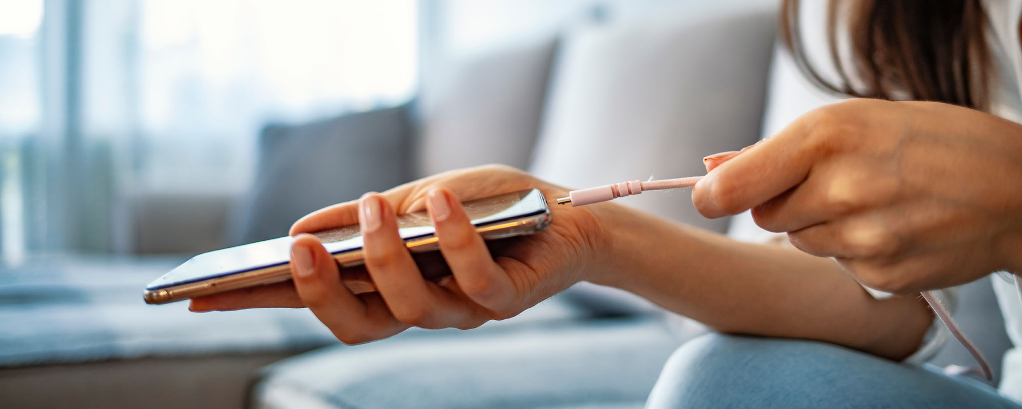 A woman's hands plugging in a phone charger