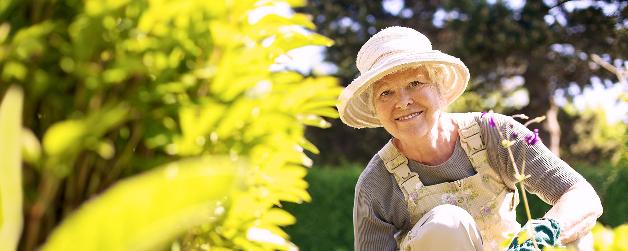 An older woman gardening in her hat and overalls