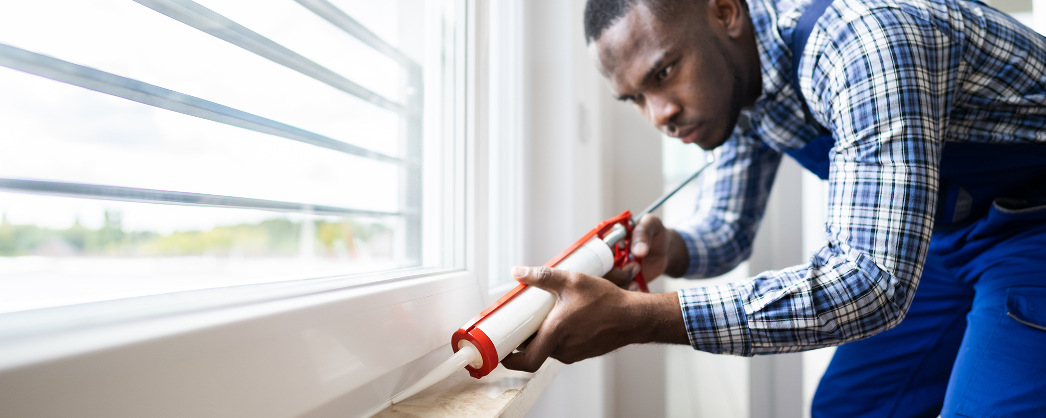 man caulking his windows