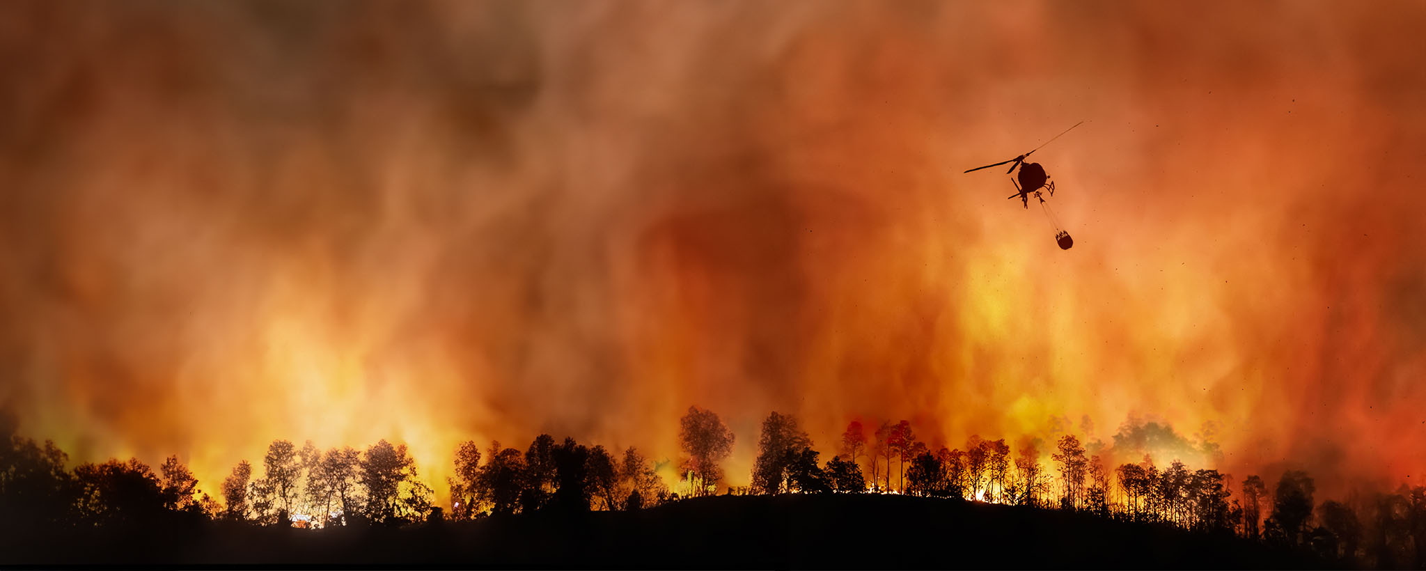 A helicopter drops water on a wildfire. 