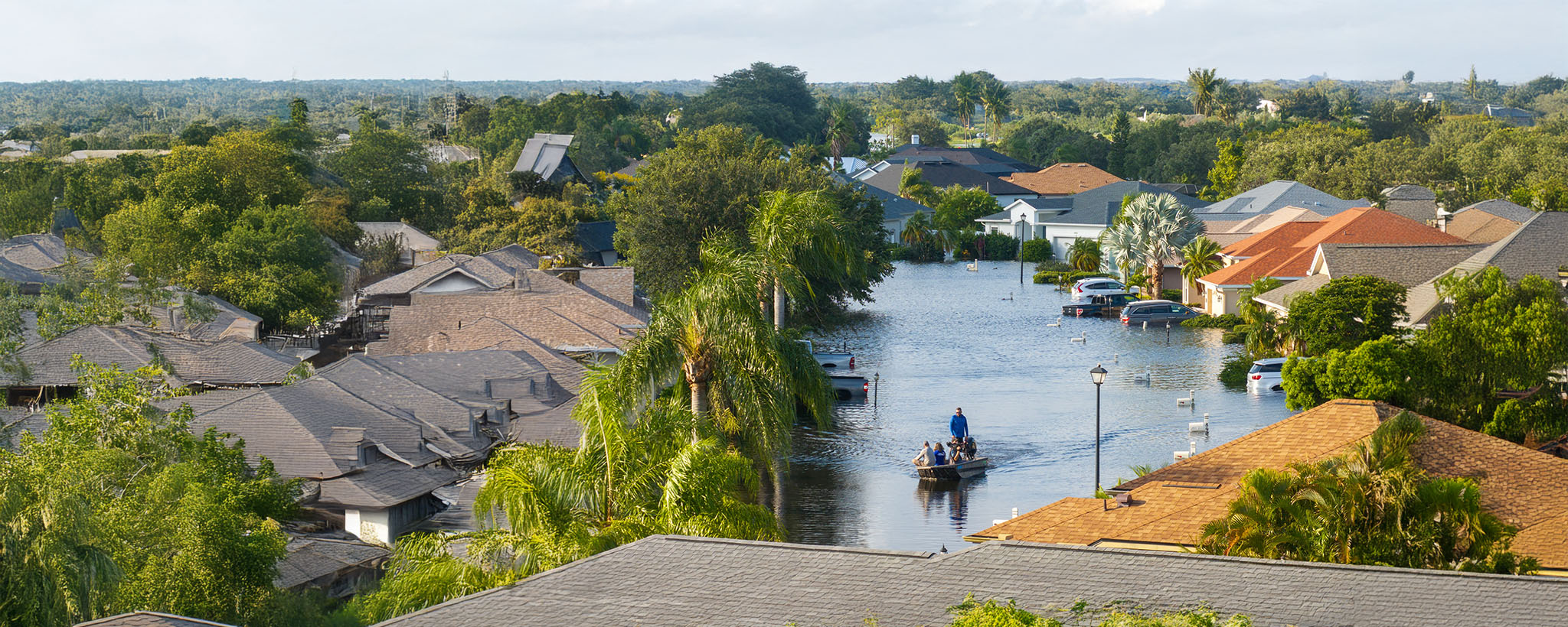 People kyacking through a neighborhood that has been severely flooded. 