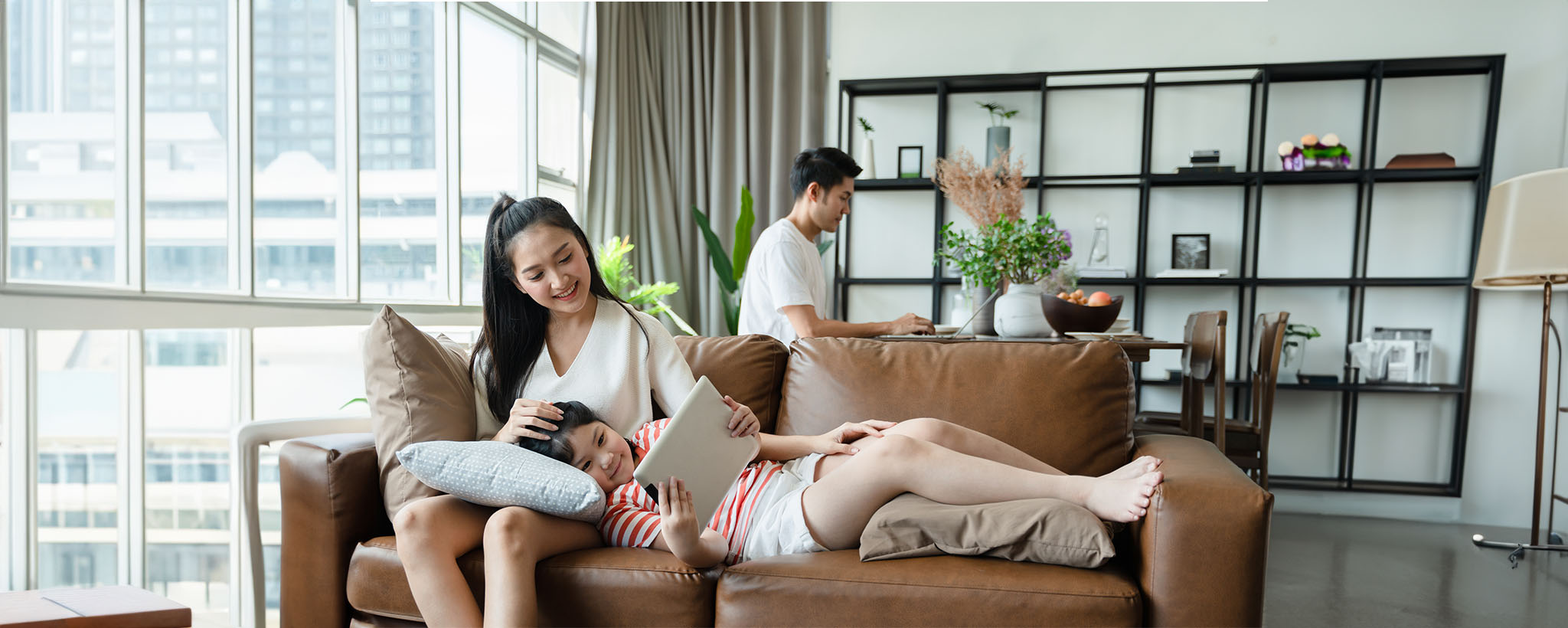 A family sitting in their living room, the daughter looks at a tablet. 