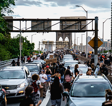 protesters walk through lines of cars