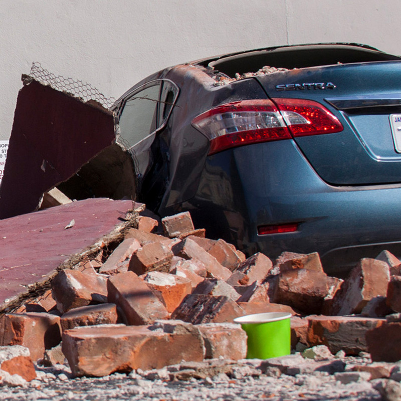 a damaged car under rubble from an earthquake