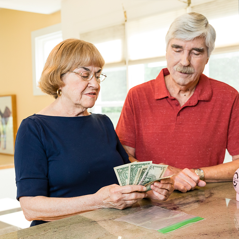 An older man and a woman count money for their emergency supply kit.