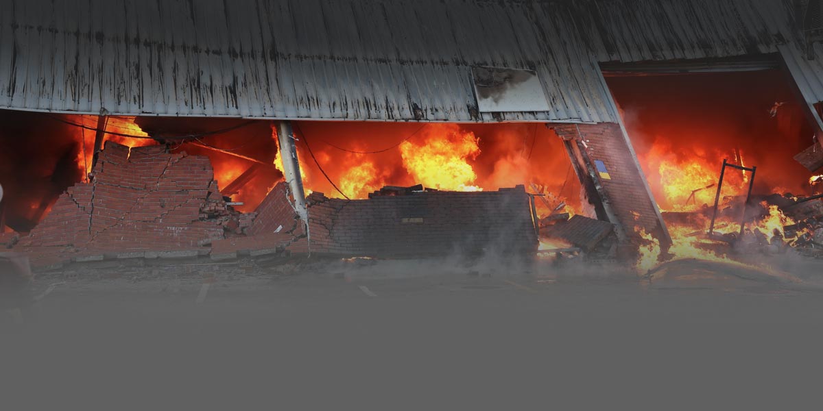 Photo of a burning warehouse building with a fire blazing inside.