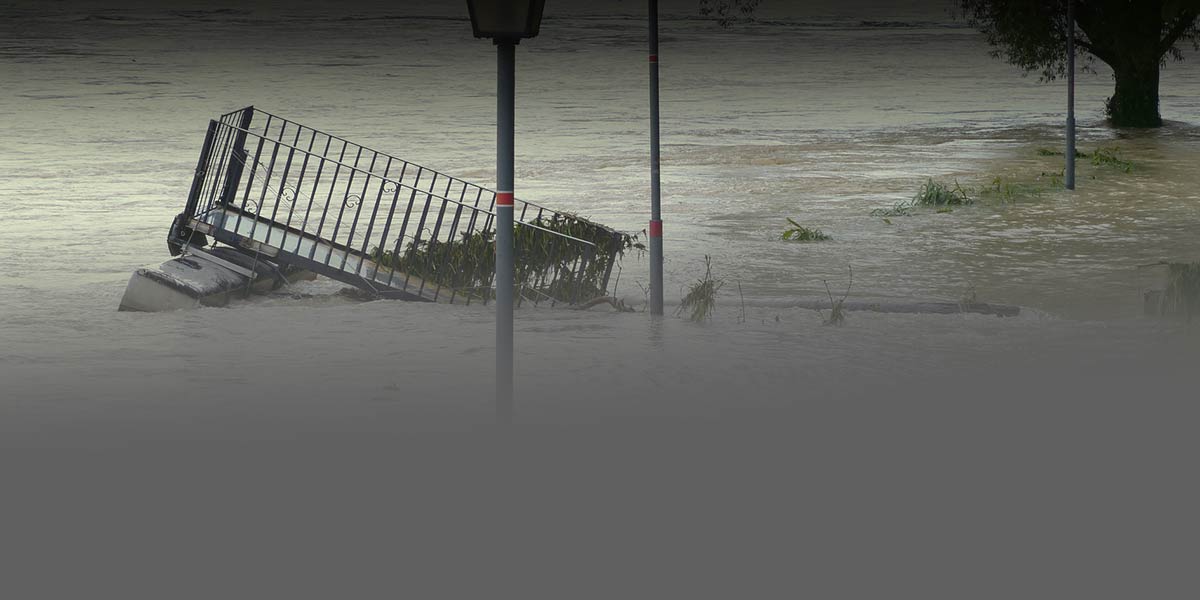 Photo of a flooded street with cars and street signs mostly under water. 