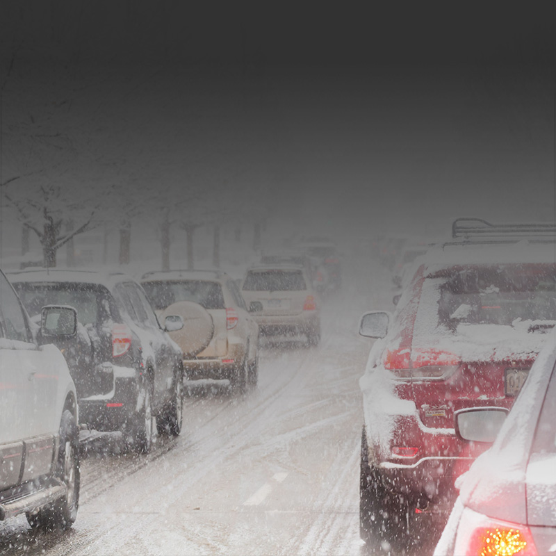 Two rows of cars on a snow covered road in traffic.