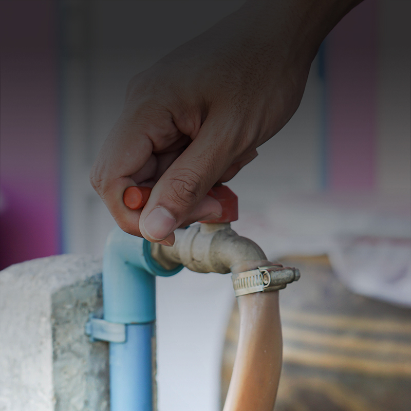 close up picture of a hand turning off a water valve.