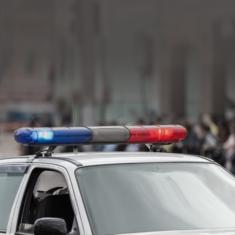 Photo of the top of a parked police car with its sirens on.