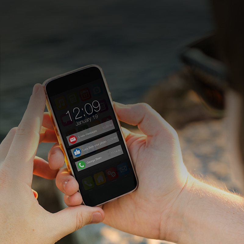 Close up image of a man holding his smart phone, showing push alerts.
