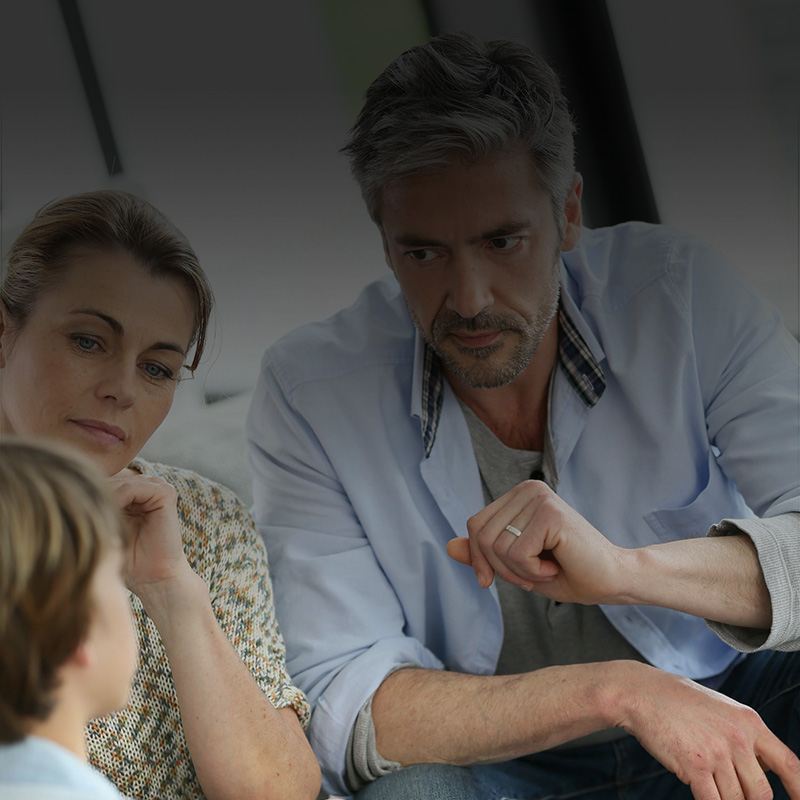 Picture of a family, mother father and son, having a serious conversation.