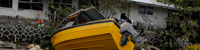 Sept 29th, 2009. A small, yellow fishing boat, lifted by tsunami waves, crashed into the stone wall of a single family home.