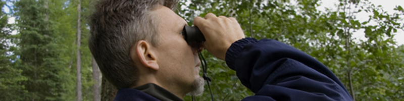 September 14th, 2003. A man peers through a pair of black binoculars.