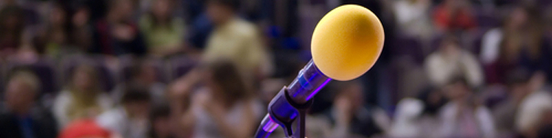 June 3rd, 2008. A microphone on stage with a crowd of people in the background.
