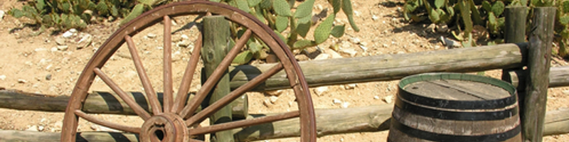 July 13, 2004. An old wheel and barrel rest against a wooden fence in the desert. July 13, 2004. An old wheel and barrel rest against a wooden fence in the desert.