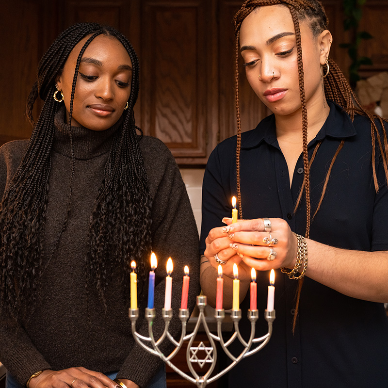 Two women lighting a menorah
