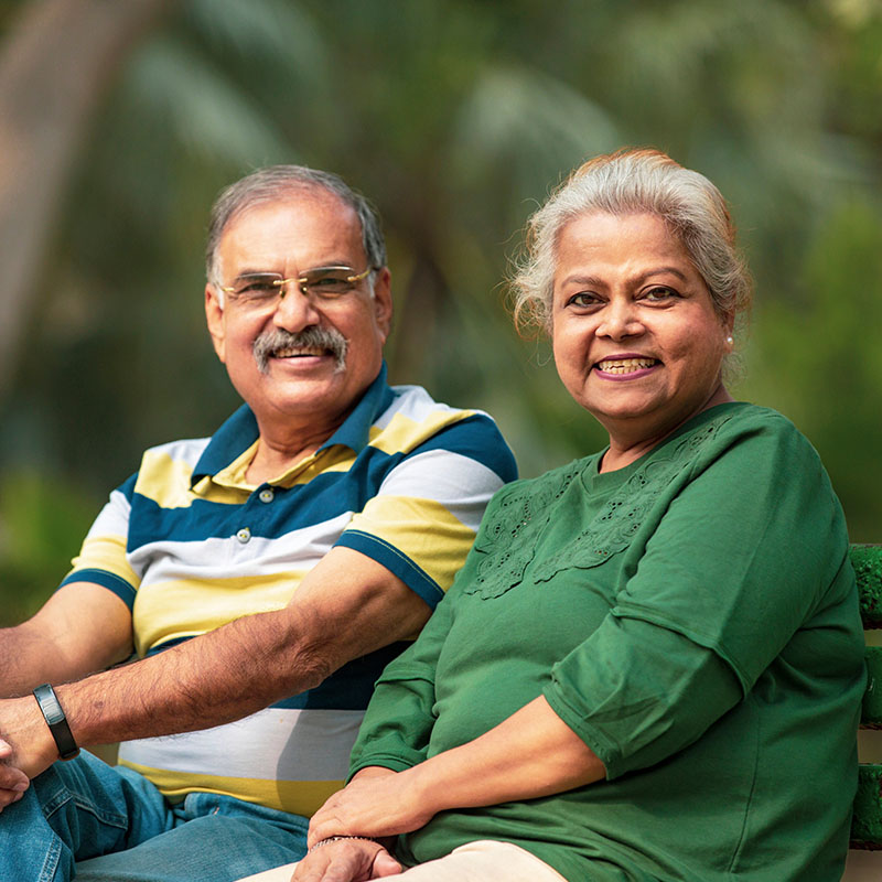 An older couple sits on a park bench. 