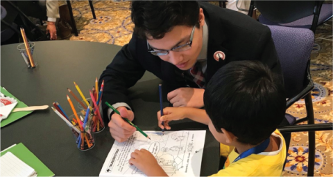 An adult helps a child with a worksheet. 