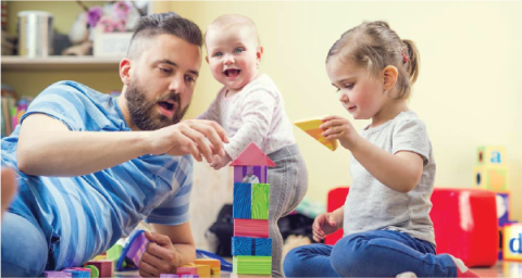 Father sitting on the floor with two small children playing with blocks
