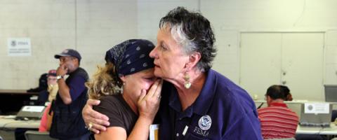 A FEMA worker comforts someone who has just been through a disaster.