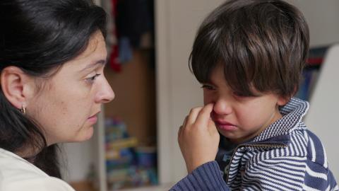 A young boy is crying as his mother tries to comfort him.