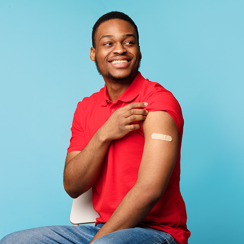 A man holding up his sleeve to show a band aid where he was just vaccinated